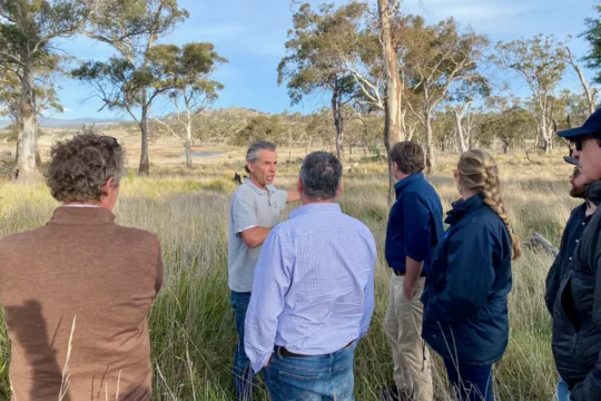 Group gathered around a man talking in a field