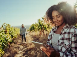 Woman in a field of crops looking at an iPad
